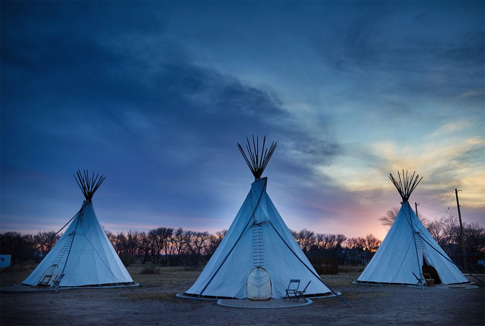 Three Tee pees in a field at dusk